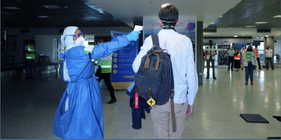 con protocolos de seguridad Mujer toma temperatura a pasajero ne aeropuerto 